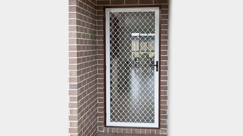 A hinged diamond grille screen door in white